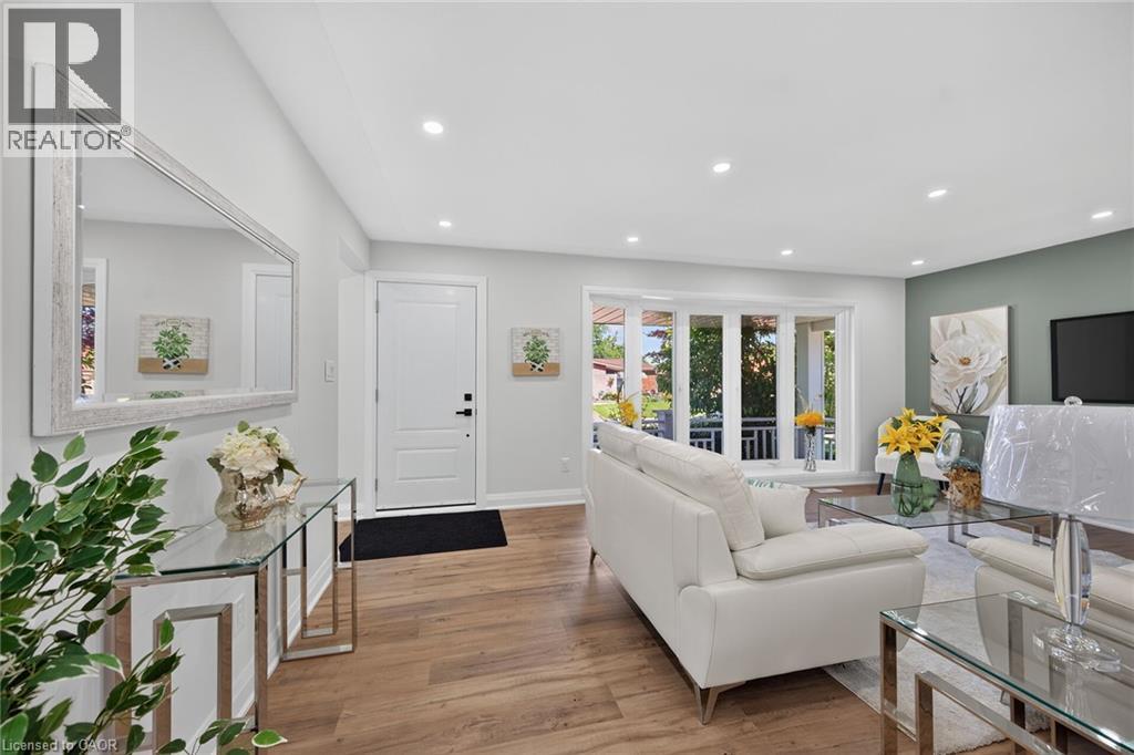 Bright living area featuring wood-finish flooring, recessed lighting, a front entry door, a bay window, and a feature wall with accent paint - 101 Loyalist Drive, Hamilton, ON - Indoor Photo Showing Living Room