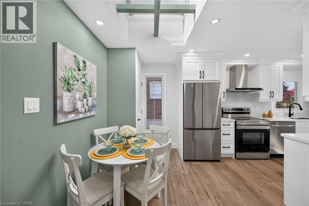 Modern kitchen featuring white cabinetry, stainless steel appliances, wood-finish flooring, and a skylight - 101 Loyalist Drive, Hamilton, ON - Indoor Photo Showing Other Room