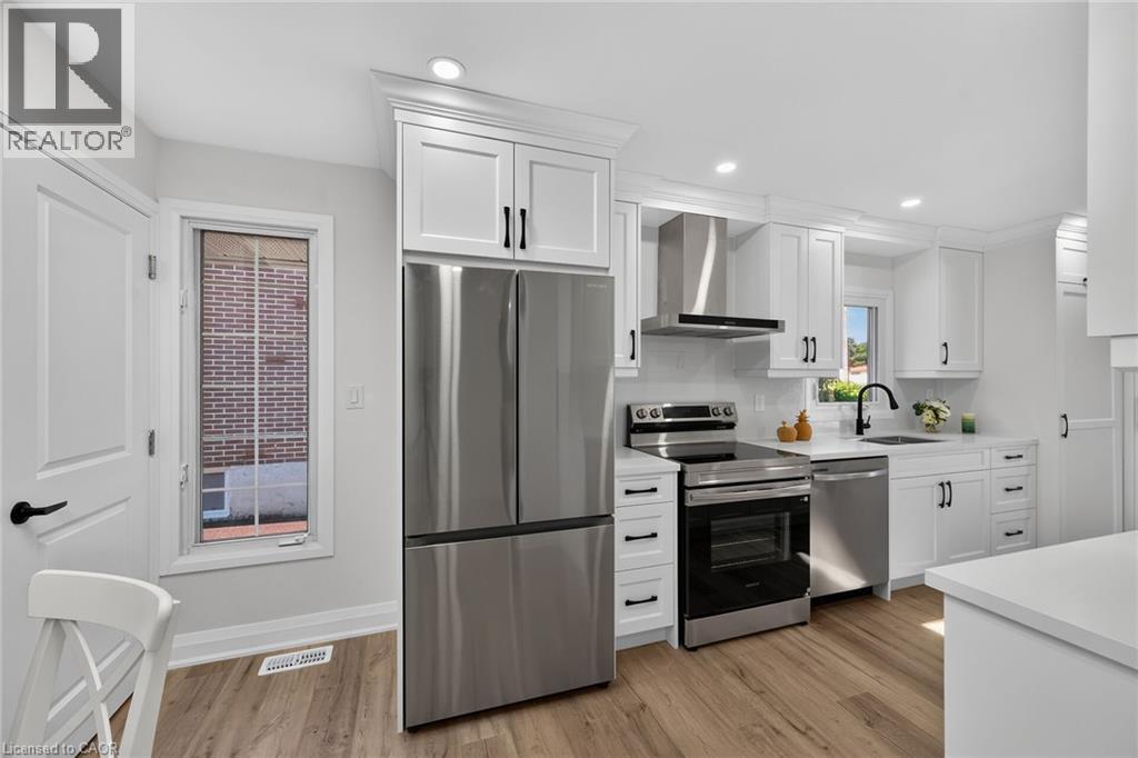 Modern kitchen featuring white shaker cabinetry, stainless steel appliances, wood-finish flooring, recessed lighting, and a black gooseneck faucet - 101 Loyalist Drive, Hamilton, ON - Indoor Photo Showing Kitchen
