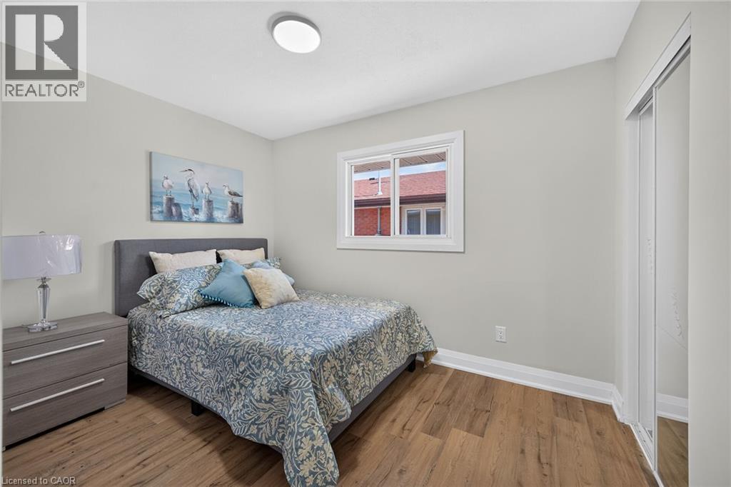 Room featuring wood-finish flooring, a double window, and a sliding mirrored closet door - 101 Loyalist Drive, Hamilton, ON - Indoor Photo Showing Bedroom