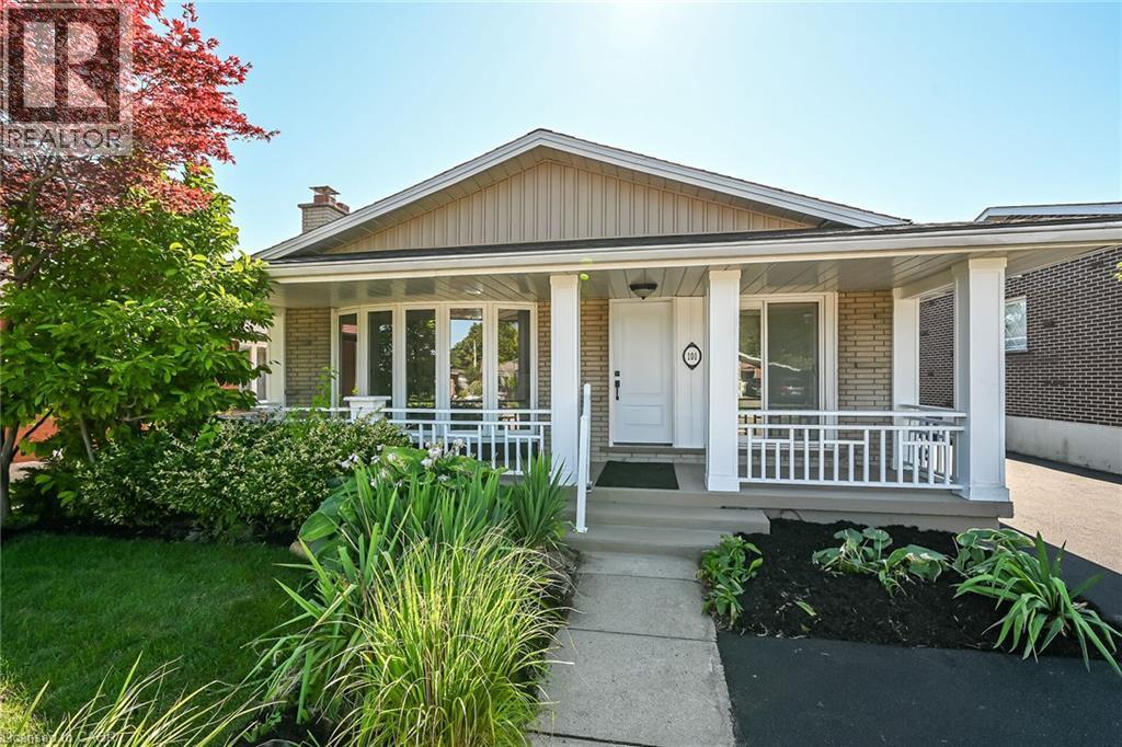 Front exterior featuring a covered porch with white railing, light-colored brick facade, and a bay window - 101 Loyalist Drive, Hamilton, ON - Outdoor With Deck Patio Veranda