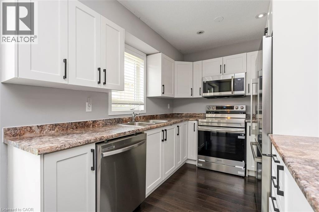 Kitchen with white shaker-style cabinetry, stainless steel appliances, and dark wood-finish flooring - 2248 Seton Crescent, Burlington, ON - Indoor Photo Showing Kitchen With Stainless Steel Kitchen With Double Sink