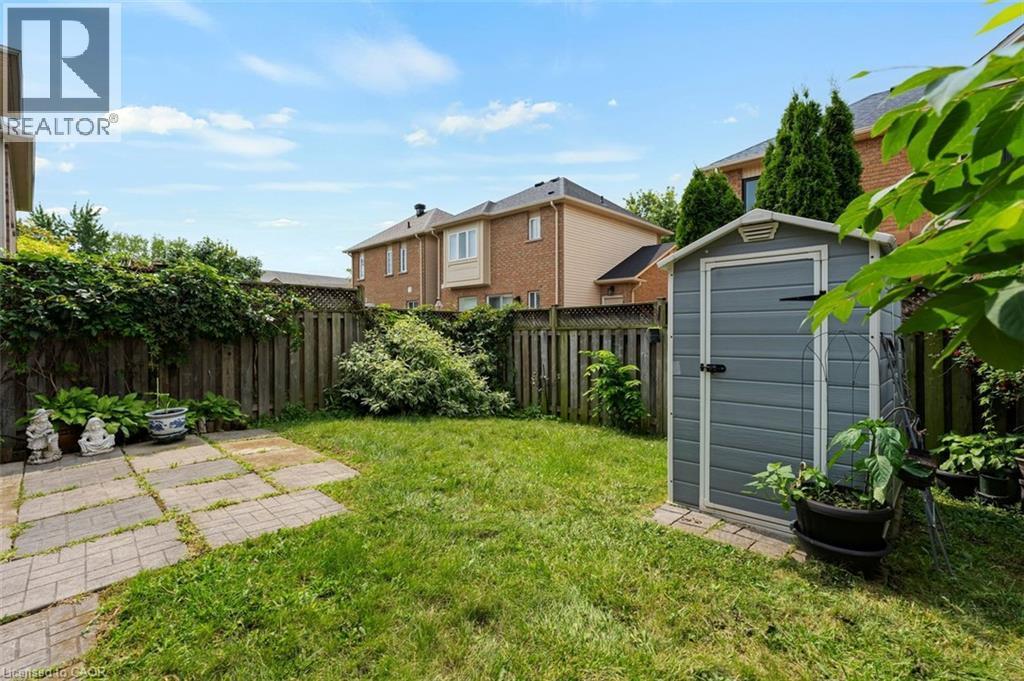 Fenced backyard with a gray storage shed, a stone paver patio, and mature perimeter foliage - 2248 Seton Crescent, Burlington, ON - Outdoor