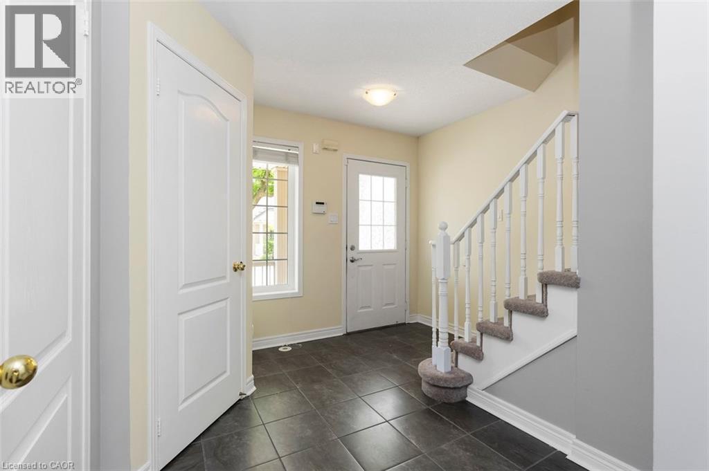 Entryway featuring dark square tile flooring, a white paneled door with a frosted glass insert, and a staircase with white balusters and carpeted treads - 2248 Seton Crescent, Burlington, ON - Indoor Photo Showing Other Room