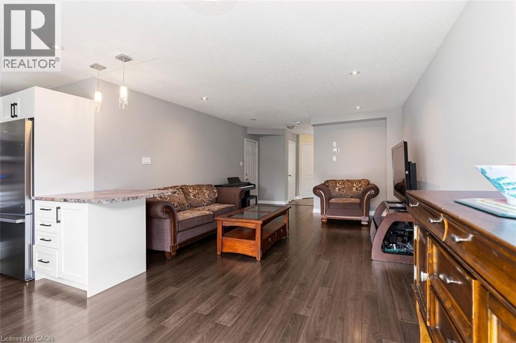 Open-concept living area featuring dark wood-finish flooring, recessed ceiling lights, and light gray wall paint - 2248 Seton Crescent, Burlington, ON - Indoor