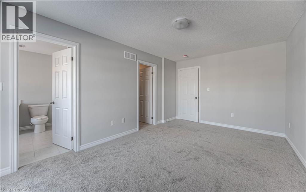 Spacious room featuring light grey carpeting, white baseboards, and a neutral wall color - 44 Harrison Drive, Cambridge, ON - Indoor Photo Showing Other Room