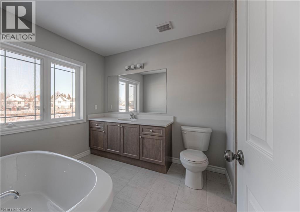 Contemporary bathroom featuring a large window, tiled flooring, an oval soaking tub, a single-sink vanity with storage, and a toilet - 44 Harrison Drive, Cambridge, ON - Indoor Photo Showing Bathroom