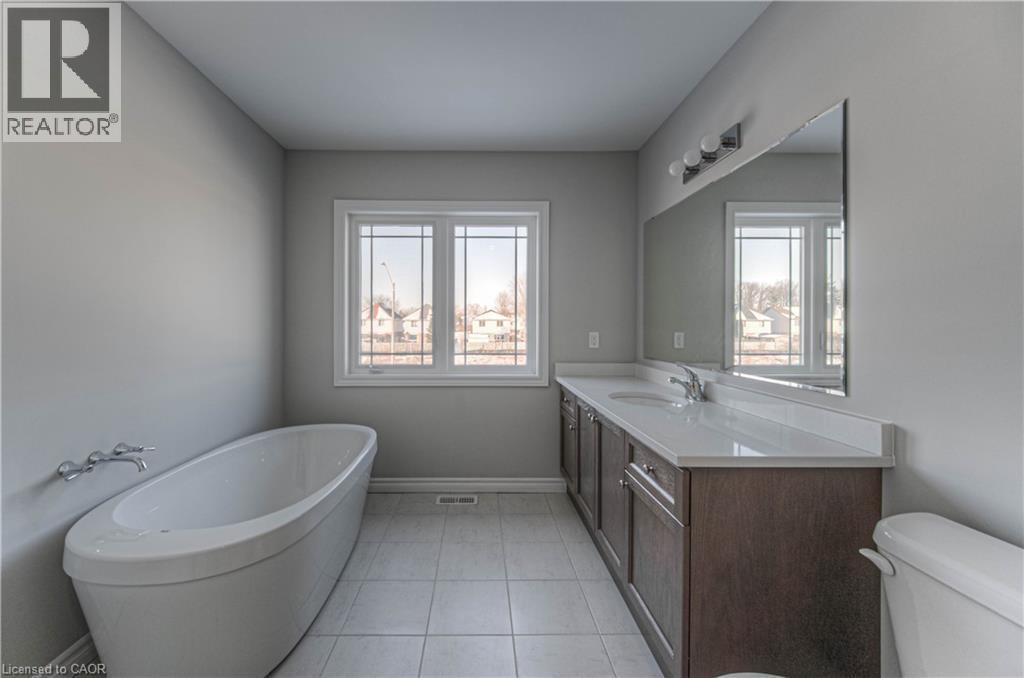 Spacious bathroom featuring a freestanding soaking tub, a double vanity with ample counter space, a large wall-mounted mirror, and tile flooring - 44 Harrison Drive, Cambridge, ON - Indoor Photo Showing Bathroom