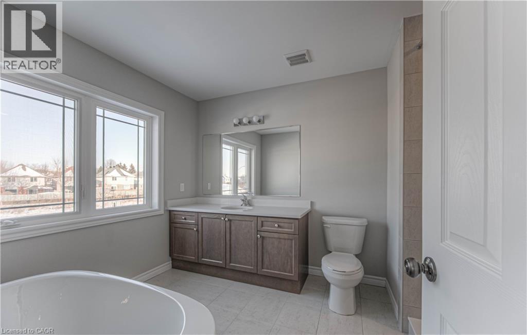 Bathroom featuring a double vanity with stone-finish countertop, undermount sink, and wood-finish cabinetry - 44 Harrison Drive, Cambridge, ON - Indoor Photo Showing Bathroom