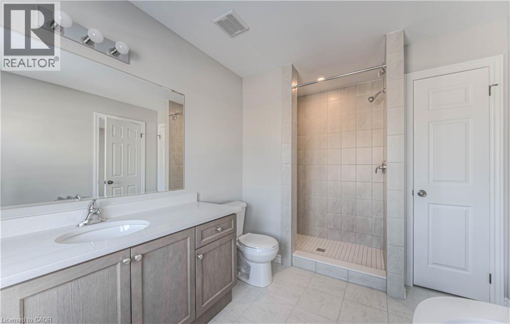 Bright bathroom featuring a single vanity with stone-finish countertop, undermount sink, and chrome faucet - 44 Harrison Drive, Cambridge, ON - Indoor Photo Showing Bathroom