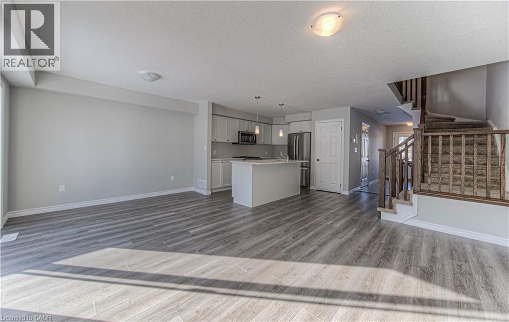 Open-concept living area featuring wood-finish flooring and light gray walls - 44 Harrison Drive, Cambridge, ON - Indoor