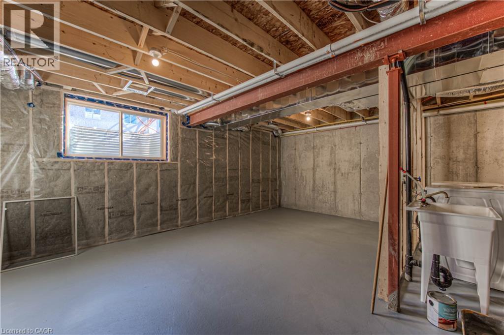 Spacious unfinished basement offering exposed wood joists, concrete walls, and a utility sink - 44 Harrison Drive, Cambridge, ON - Indoor Photo Showing Basement