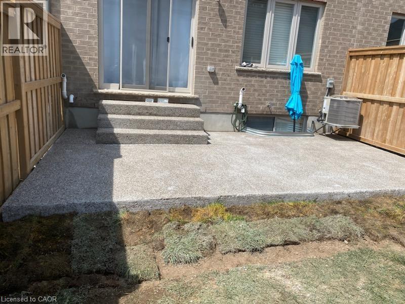 Expansive concrete patio with multiple steps leading to a sliding glass door - 44 Harrison Drive, Cambridge, ON - Outdoor