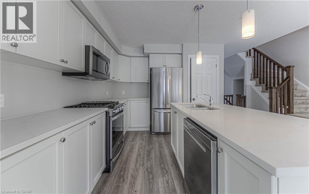 Kitchen featuring light cabinetry, stainless steel appliances, an island with an undermount sink, pendant lighting, and wood-finish flooring - 44 Harrison Drive, Cambridge, ON - Indoor Photo Showing Kitchen With Stainless Steel Kitchen With Double Sink With Upgraded Kitchen