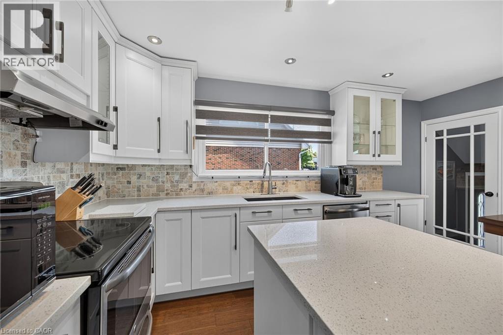 Kitchen featuring white shaker cabinetry, light-toned countertops, a mosaic tile backsplash, and a center island - 386 Upper Kenilworth Avenue, Hamilton, ON - Indoor Photo Showing Kitchen With Upgraded Kitchen