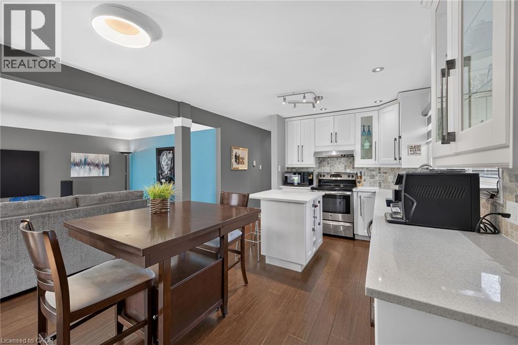Open-concept kitchen featuring white cabinetry, stone countertops, a tiled backsplash, and stainless steel appliances - 386 Upper Kenilworth Avenue, Hamilton, ON - Indoor