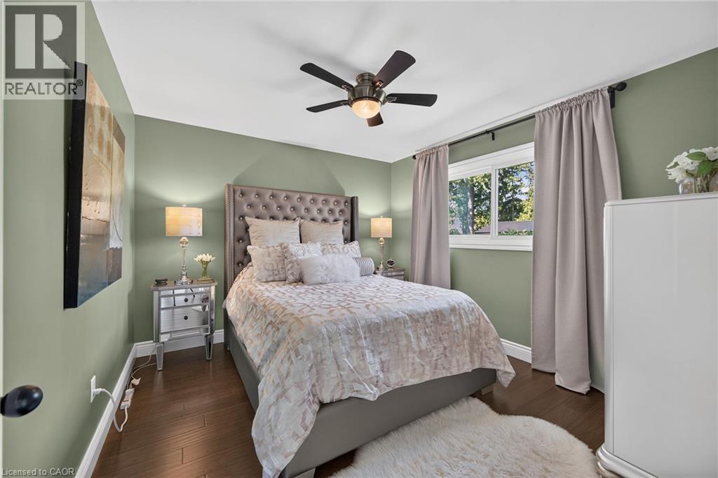 Wood-finish flooring with baseboard trim, wall-mounted ceiling fan, and a double-pane window - 386 Upper Kenilworth Avenue, Hamilton, ON - Indoor Photo Showing Bedroom