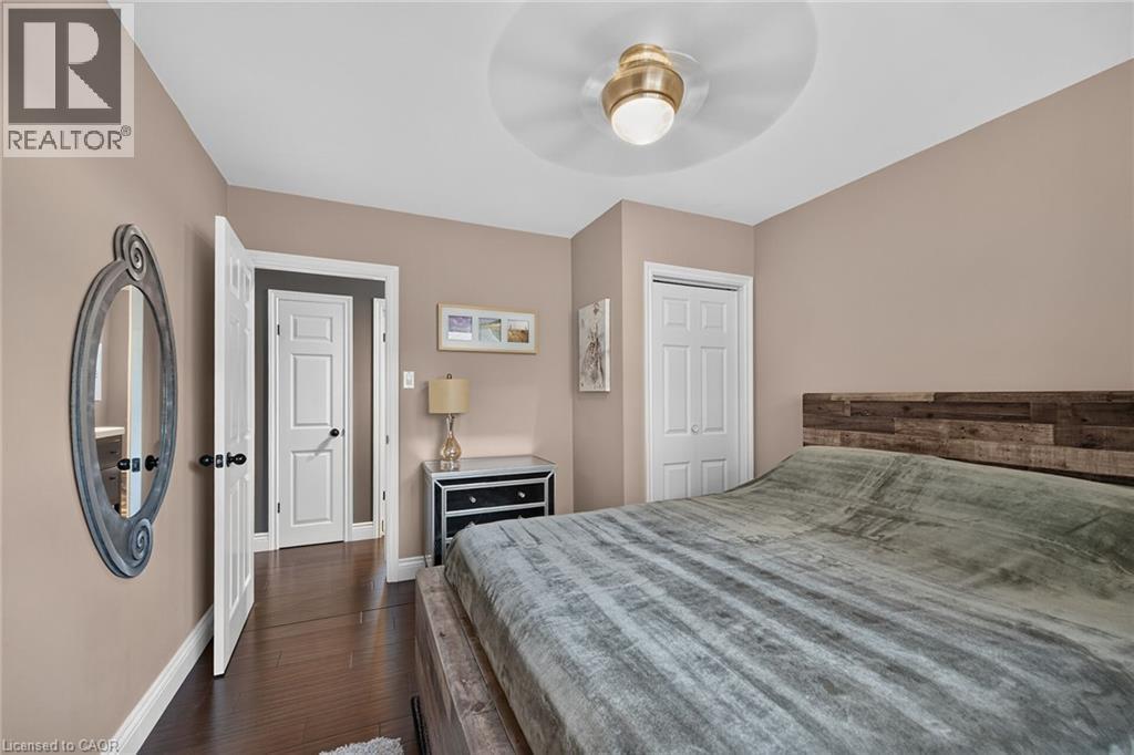 Spacious room featuring wood-finish flooring, a contemporary ceiling fan, and a paneled white door - 386 Upper Kenilworth Avenue, Hamilton, ON - Indoor Photo Showing Bedroom