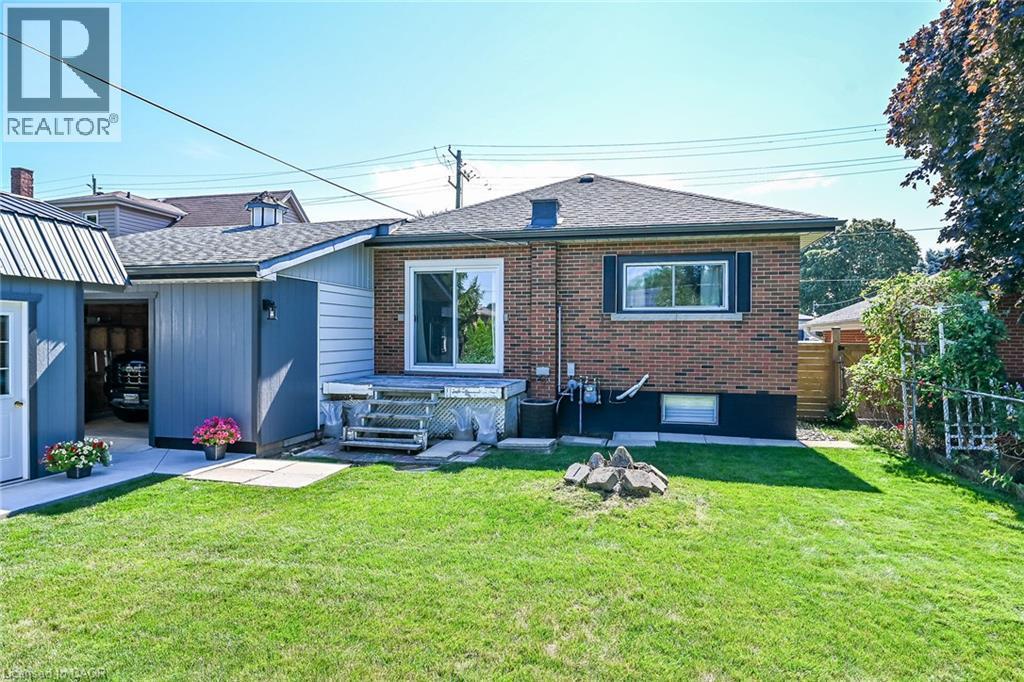 Expansive rear yard featuring a brick facade, sliding glass door, and a detached garage with a metal roof - 386 Upper Kenilworth Avenue, Hamilton, ON - Outdoor