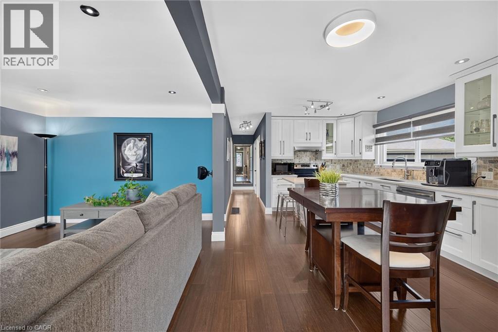 Open-concept living space featuring wood-finish flooring, recessed lighting, white perimeter cabinetry, a mosaic tile backsplash, and an undermount sink - 386 Upper Kenilworth Avenue, Hamilton, ON - Indoor