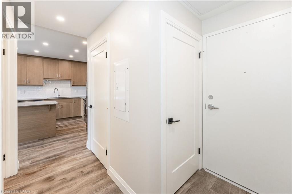 Entryway featuring wood-finish flooring, white doors with matte black hardware, and recessed lighting - 72 Erb Street E Unit# 103, Waterloo, ON - Indoor