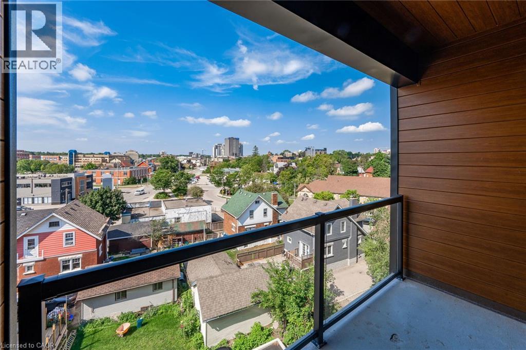 Balcony featuring a glass railing, concrete flooring, and wood-finish wall panels - 72 Erb Street E Unit# 103, Waterloo, ON - Outdoor With Balcony With Exterior