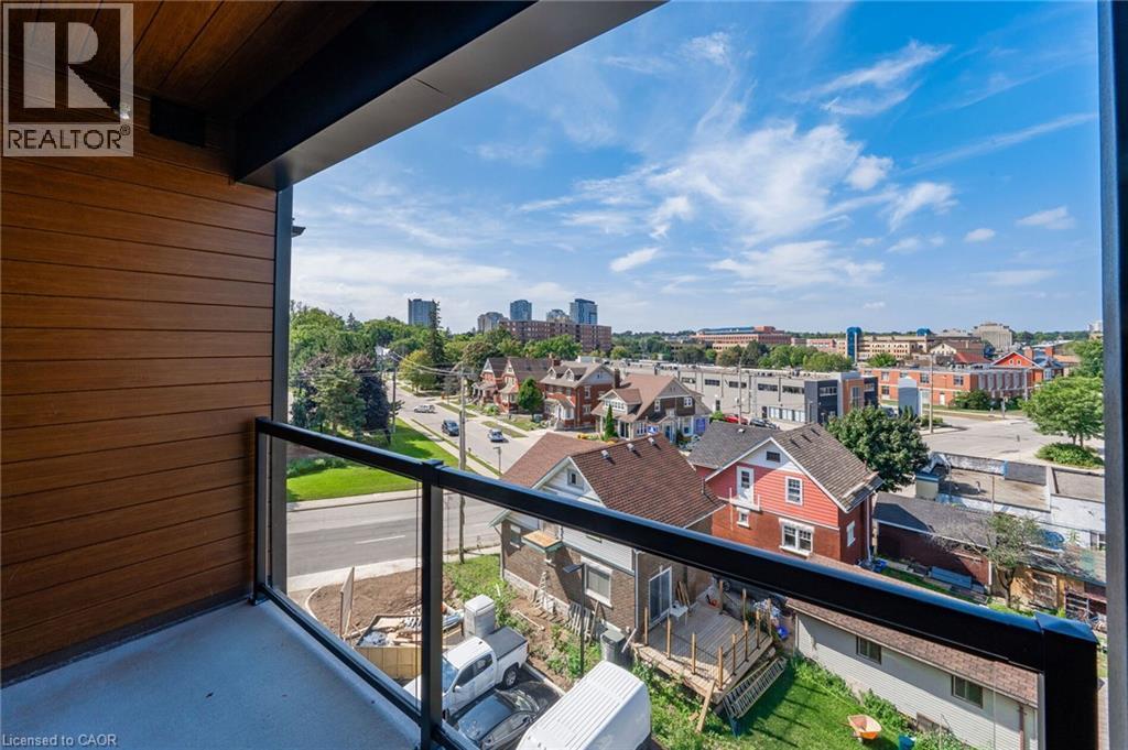 Balcony featuring wood-finish siding, a dark soffit with recessed lighting, and a glass panel railing with a black metal frame - 72 Erb Street E Unit# 103, Waterloo, ON - Outdoor With Balcony With Exterior