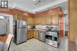 Kitchen featuring wood cabinetry, stainless steel appliances, tile flooring, and a subway tile backsplash -