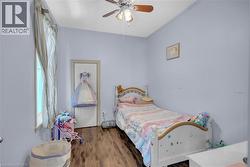 Interior room featuring wood-finish flooring, light blue wall paint, and a ceiling fan with integrated lighting -