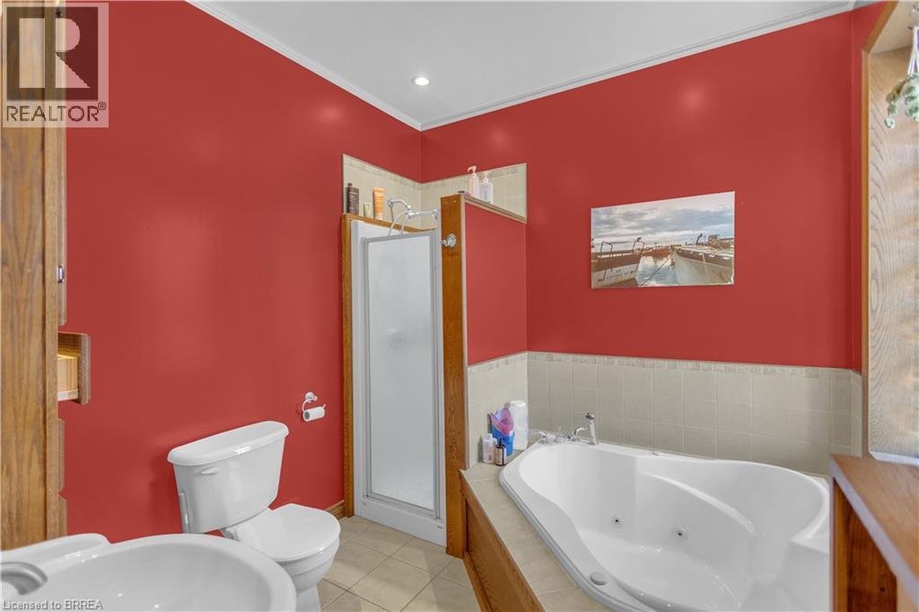 Bathroom featuring a jetted soaking tub, walk-in shower with frosted glass enclosure, and wood-finish cabinetry - 17 Scarfe Avenue, Brantford, ON - Indoor Photo Showing Bathroom