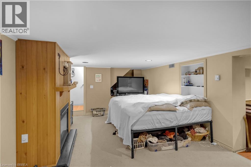 Finished basement area featuring a wood-paneled fireplace surround, recessed lighting, and a built-in shelving unit - 17 Scarfe Avenue, Brantford, ON - Indoor Photo Showing Bedroom