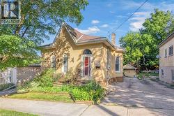 Brick exterior with arched windows, a covered front porch, and an asphalt driveway -