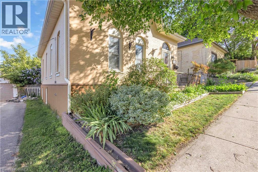 Brick exterior featuring arched windows, mature landscaping, and an established sidewalk - 17 Scarfe Avenue, Brantford, ON - Outdoor