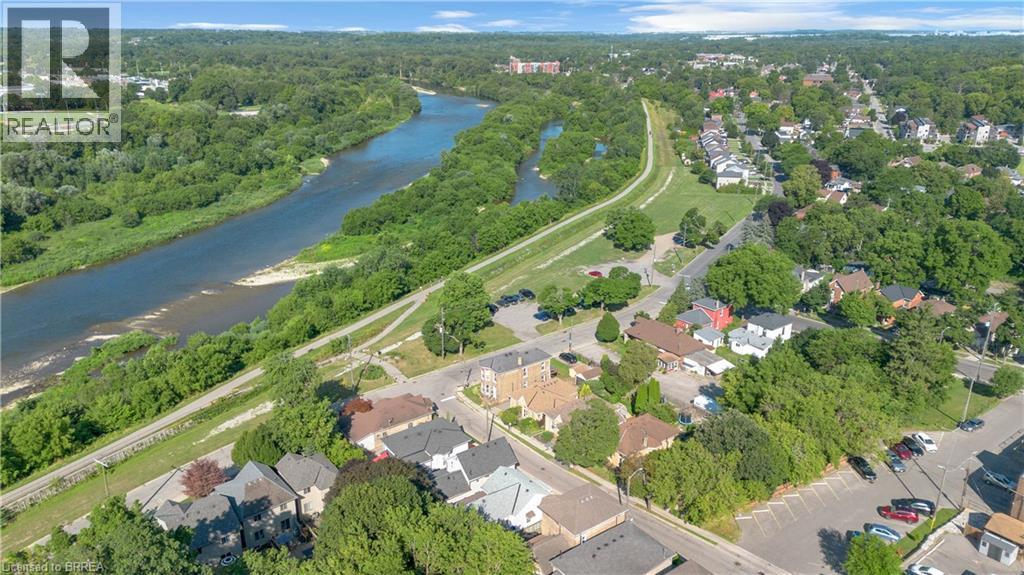 Aerial panorama showcasing a winding river bordered by extensive green spaces and residential development - 17 Scarfe Avenue, Brantford, ON - Outdoor With Body Of Water With View