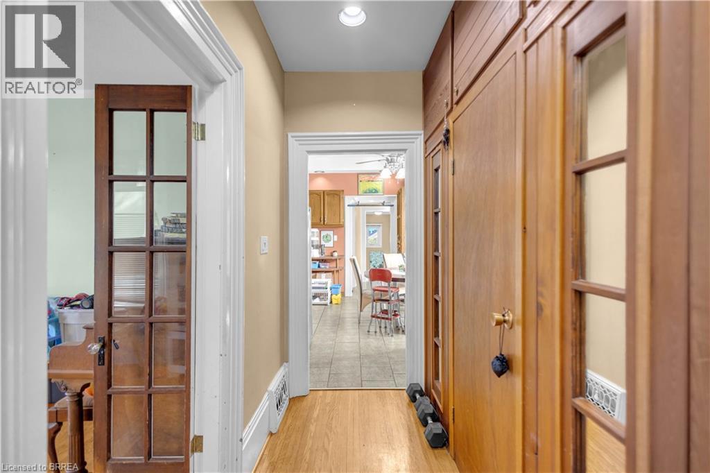 Hallway featuring wood-finish flooring, built-in cabinetry with glass-paneled doors, white baseboards, and neutral wall paint - 17 Scarfe Avenue, Brantford, ON - Indoor Photo Showing Other Room