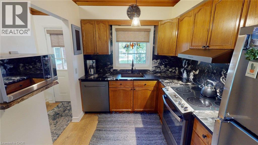 Kitchen featuring wood cabinetry and dark countertops with a coordinating backsplash - 4101 Diana Park, Vineland, ON - Indoor Photo Showing Kitchen