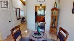 Open-concept dining area featuring light wood-finish flooring, a vaulted ceiling with exposed wood beams, and an arched doorway -