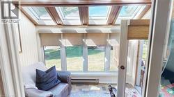 Sunroom featuring multiple skylights, paneled walls, and tiled flooring -
