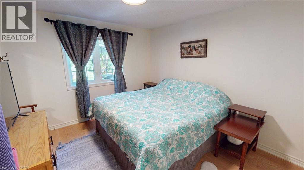 Bright room featuring a window with dark drapes, light wood-finish flooring, and white baseboards - 4101 Diana Park, Vineland, ON - Indoor Photo Showing Bedroom