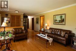 Spacious living area featuring wood-finish flooring, light-colored walls, and detailed crown molding -
