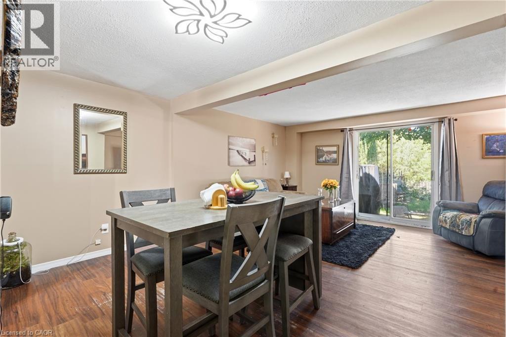 Open-concept living area featuring wood-finish flooring, a contemporary ceiling fixture, and neutral wall tones - 292 Mayview Court Unit# B, Waterloo, ON - Indoor