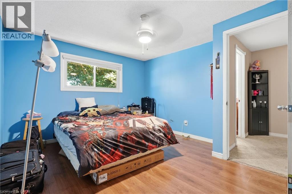 Bedroom featuring wood-finish flooring, a white trim window, and a ceiling fan with integrated lighting - 292 Mayview Court Unit# B, Waterloo, ON - Indoor Photo Showing Bedroom