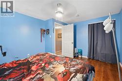 Room with wood-finish flooring, a ceiling fan, and light blue wall paint -