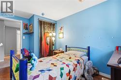 Bedroom featuring light blue walls, wood-finish flooring, a white ceiling, and a framed doorway -