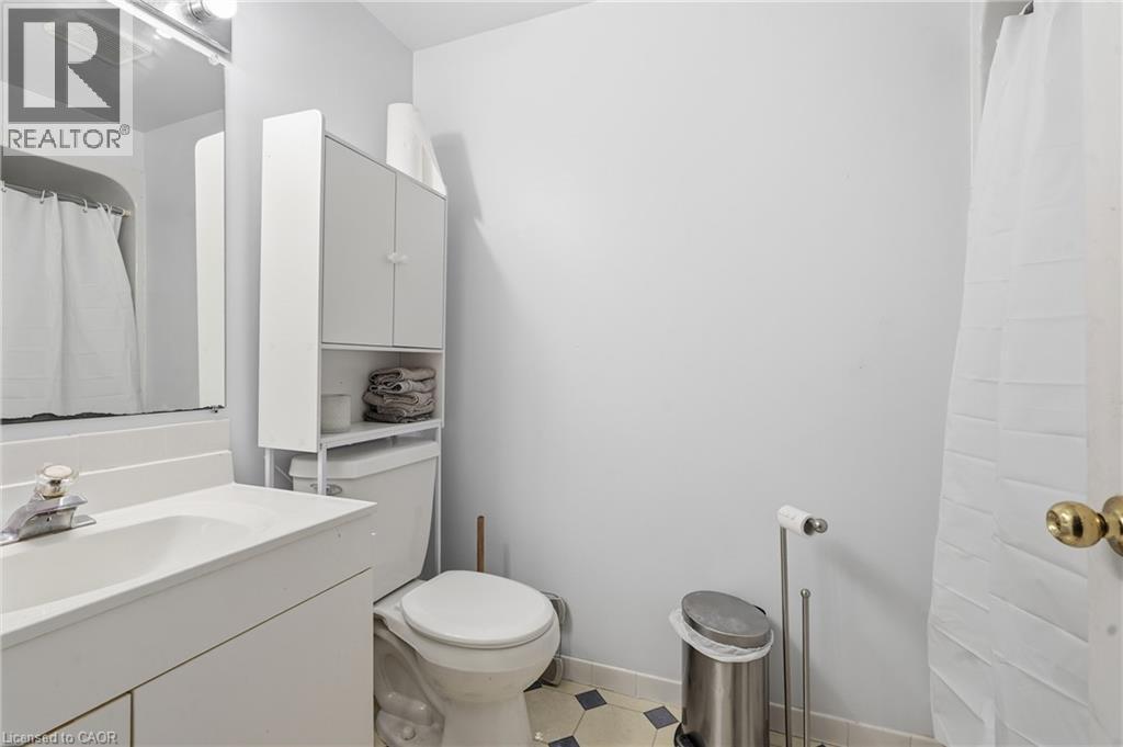 Bathroom featuring a white vanity with integrated sink, chrome faucet, wall-mounted mirror, and white over-the-toilet storage cabinetry - 292 Mayview Court Unit# B, Waterloo, ON - Indoor Photo Showing Bathroom