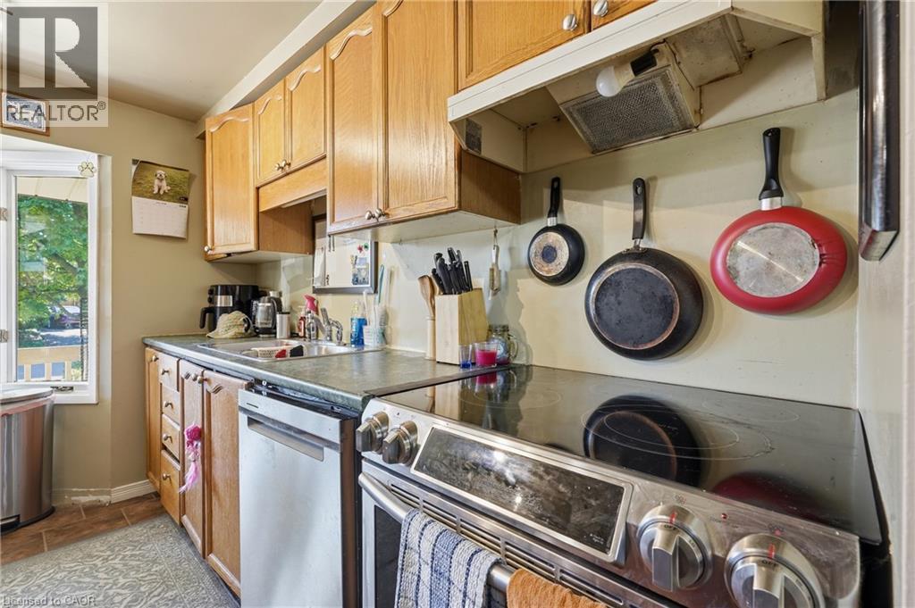 Natural wood cabinetry with brushed nickel hardware, complementing a dark countertop and stainless steel appliances - 292 Mayview Court Unit# B, Waterloo, ON - Indoor Photo Showing Kitchen