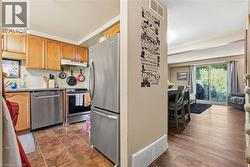 Open-concept kitchen and living area featuring stainless steel appliances, wood cabinetry, wood-finish flooring, and abundant natural light from multiple windows -