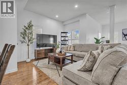Open-concept living area featuring hardwood flooring, white walls, recessed lighting, and plantation shutters -