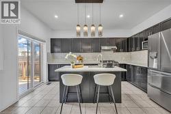 Kitchen featuring a central island with countertop seating, dark wood-finish cabinetry, light-toned backsplash, stainless steel appliances, and sliding glass doors opening to a wood deck -