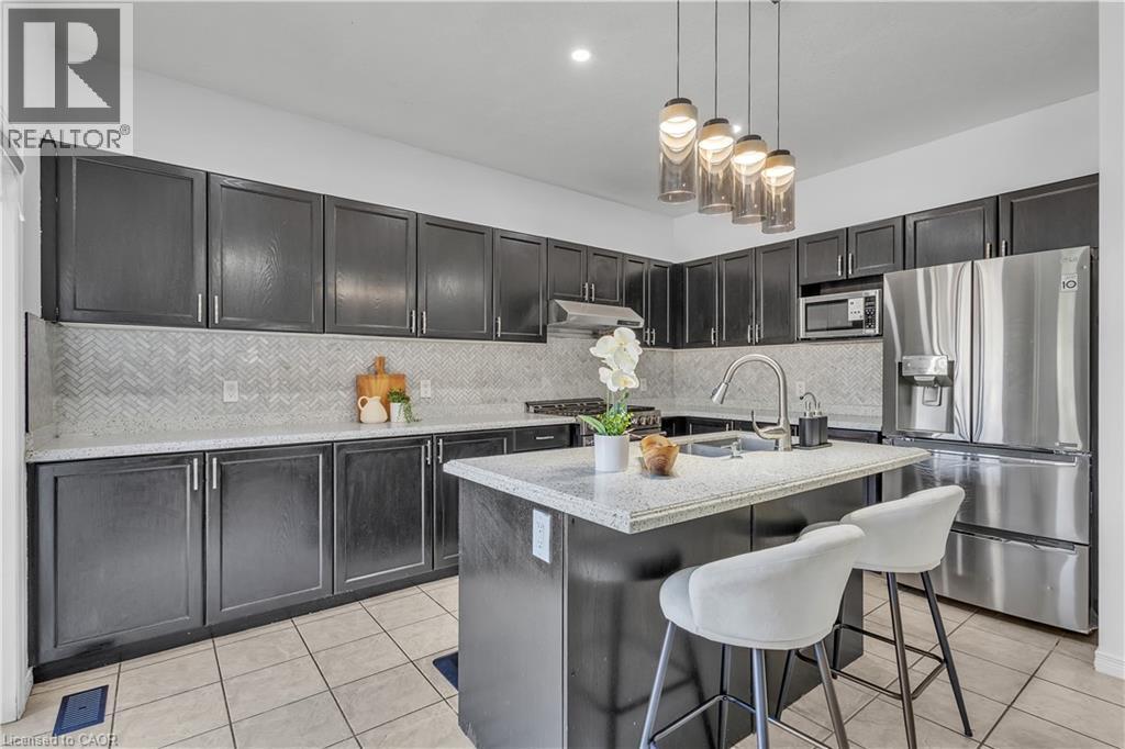 Modern kitchen featuring dark cabinetry, light countertops, and a herringbone-patterned backsplash - 73 Fitzgerald Drive, Cambridge, ON - Indoor Photo Showing Kitchen With Upgraded Kitchen